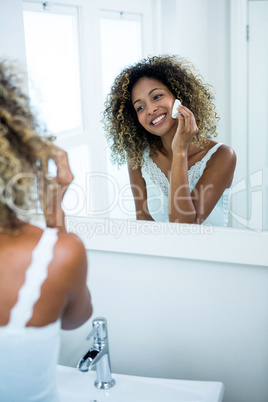 Young woman cleaning her face with sponge