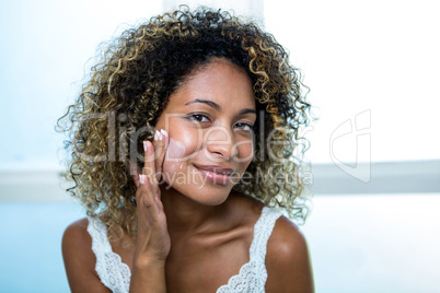 Young woman applying moisturizer