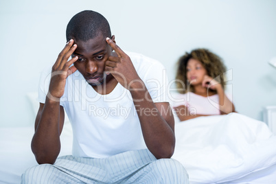 Tensed man sitting on bed in bedroom