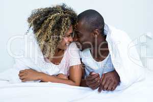 Young couple romancing face to face on bed