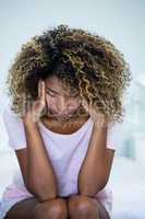 Tensed woman sitting on bed in bedroom