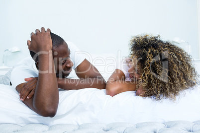 Young couple lying on bed and talking
