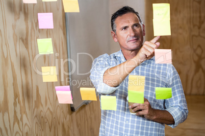 Thoughtful man reading at sticky notes while having coffee