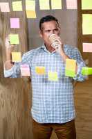 Man writing on sticky notes while having coffee