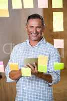Man holding digital tablet and sticky notes on window