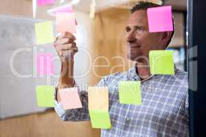 Man looking at sticky notes on window
