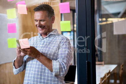 Man using mobile phone and sticky notes on window