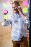 Man writing on sticky notes while talking on phone