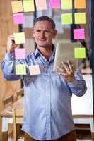 Man using digital tablet while writing on sticky notes