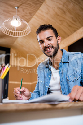 Smiling man in office writing in a notepad