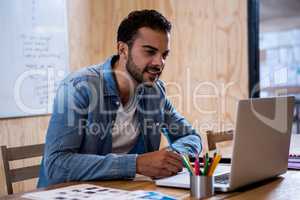 Man writing note on diary while using laptop