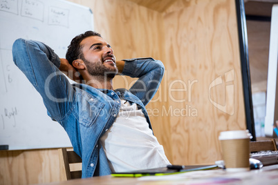 Man relaxing on chair with hands behind head