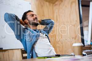 Man relaxing on chair with hands behind head