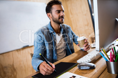 Man working on his graphics tablet and holding coffee