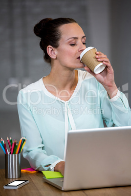 Woman using laptop while having coffee