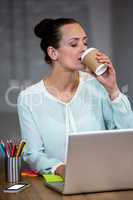 Woman using laptop while having coffee