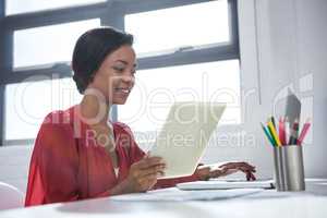 Woman using laptop and holding digital tablet