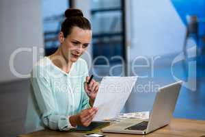 Woman looking a chart with laptop and graphics tablet on desk