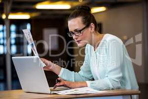 Woman looking a chart and using a laptop