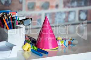 Party horn, birthday hat, pen holder and spectacle on desk