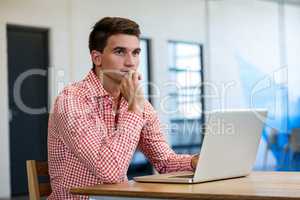 Thoughtful man using laptop in office