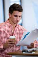 Man reading a document while having coffee