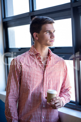 Man looking through window with coffee in hand