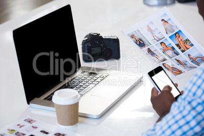 Man looking a chart with laptop and camera on desk