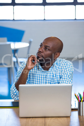 Thoughtful man sitting on table with laptop