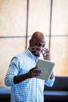 Man looking at digital tablet while talking on phone