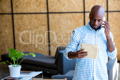 Man looking at digital tablet while talking on phone