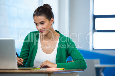 Creative woman drawing on a graphic tablet while using laptop