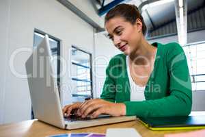 Smiling brunette typing on laptop