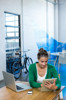 Woman using digital tablet with laptop and mobile phone on table