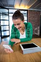 Woman using mobile phone with digital tablet on table