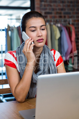 Woman talking on phone while using laptop