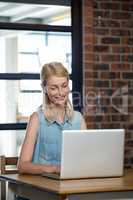 Happy woman sitting on table using laptop