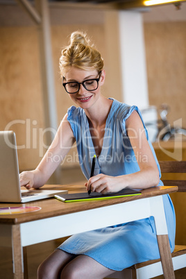 Graphic designer drawing on a graphic tablet while using laptop