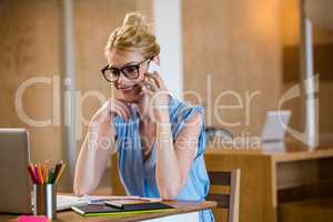 Graphic designer in office sitting at desk and talking on mobile