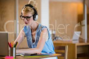 Graphic designer listening to headphones while using laptop