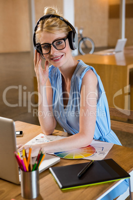 Graphic designer listening to headphones while using laptop