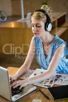 Graphic designer listening to headphones while using laptop
