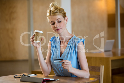Beautiful woman having coffee while online shopping