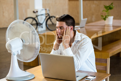 Man enjoying a breeze with laptop on desk