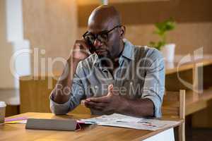 Man looking at digital tablet while talking on phone