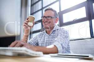 Man working on computer while having coffee in office
