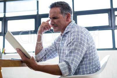 Thoughtful man looking at digital tablet