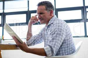 Thoughtful man looking at digital tablet