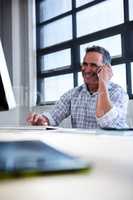 Man talking on mobile phone while using computer