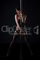 Stripper in fishnet bodysuit posing with pylon